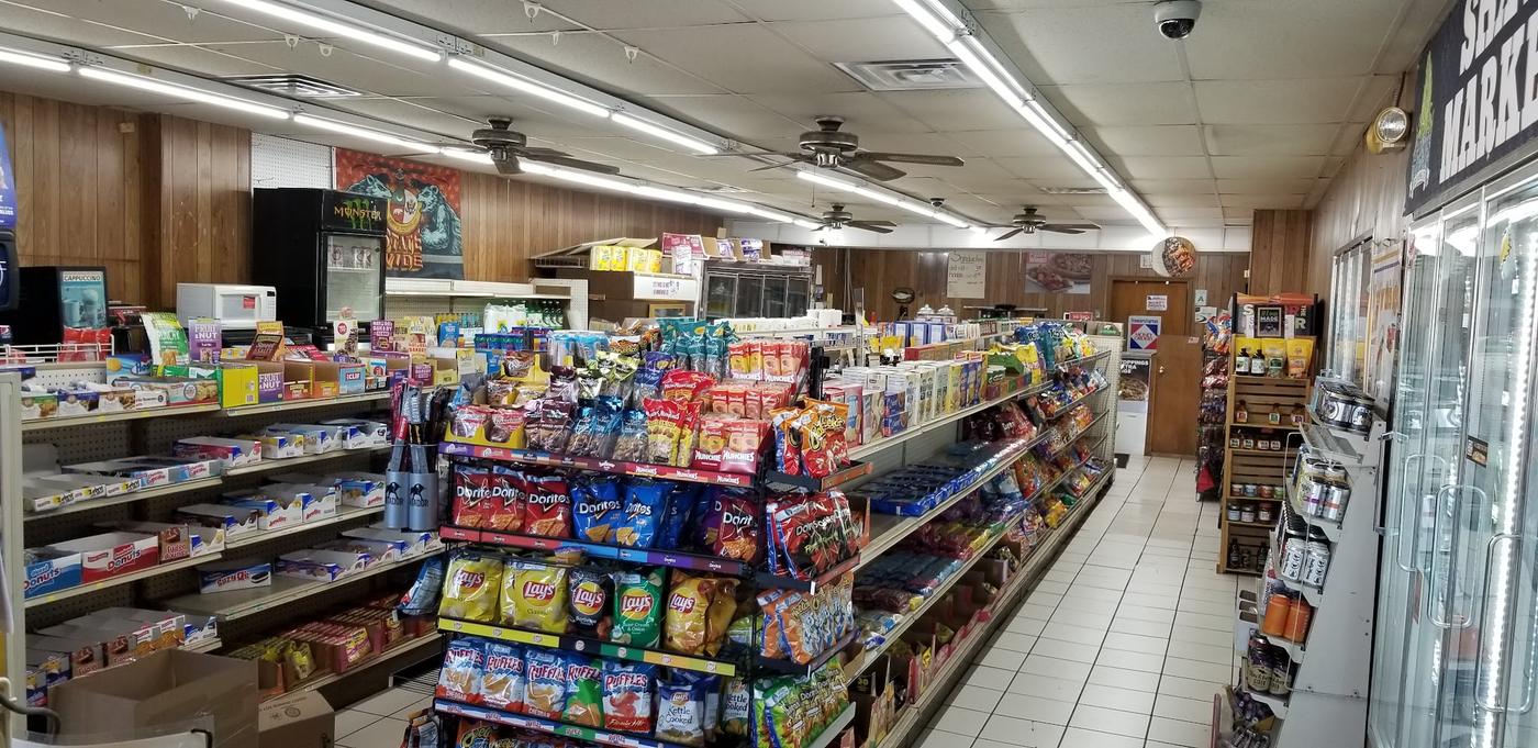 An aisle inside Shaw Market, shelves of snacks running back towards the coolers
