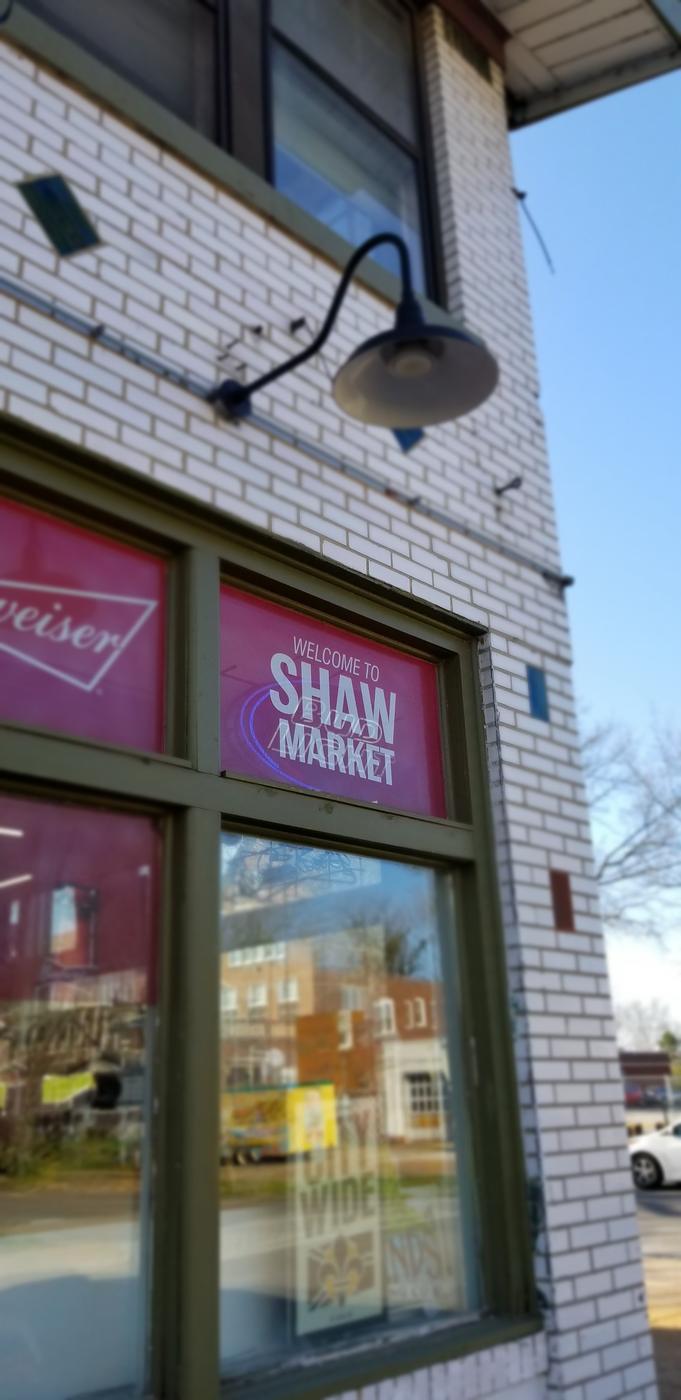 The corner of the Shaw Market building with its sign, against a blue sky